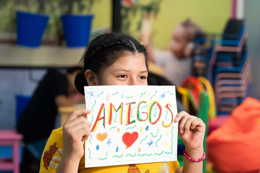 Imagen de una niña esmeraldeña sosteniendo un cartel que reza "amigos".